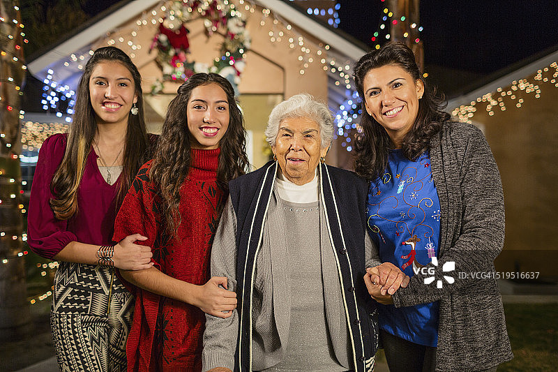 三代西班牙妇女在装饰着彩灯的房子外微笑着图片素材