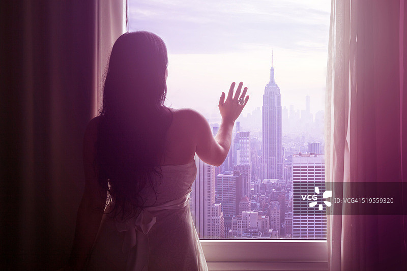 年轻女子的手放在窗户和纽约的地平线上图片素材