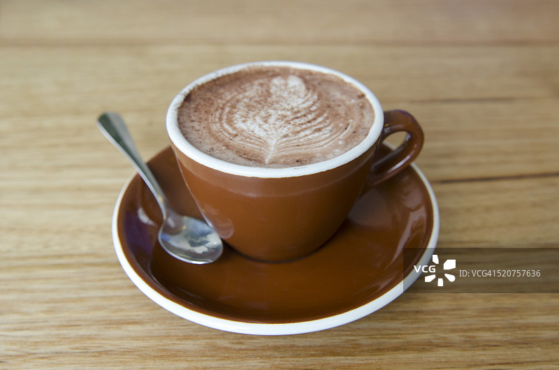 热巧克力饮料在棕色的杯子在木桌上图片素材