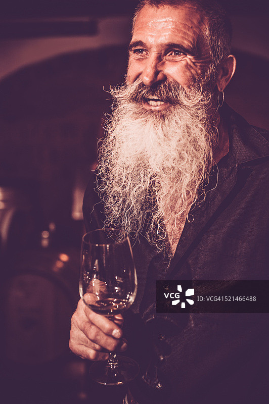 胡子老人在酒窖里举着酒杯图片素材