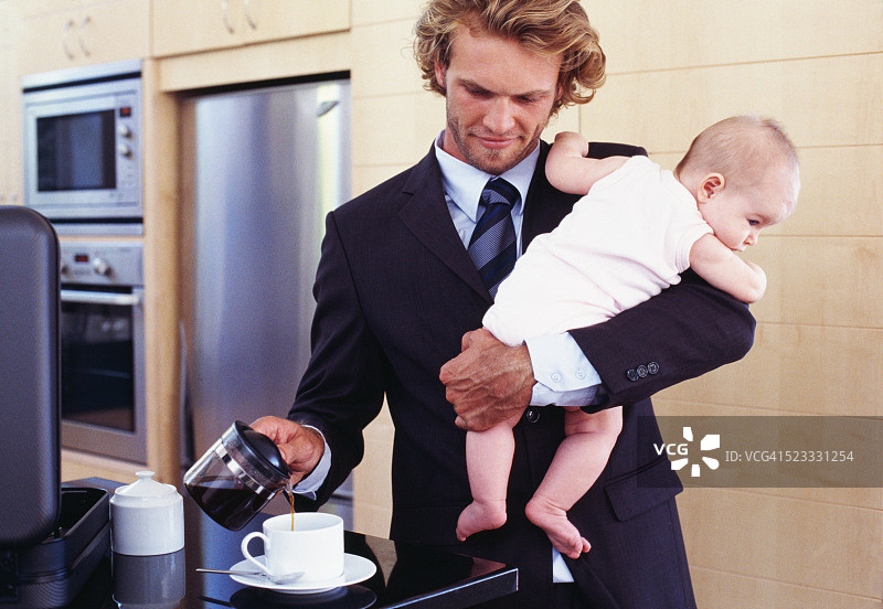 抱着婴儿倒咖啡的商人图片素材