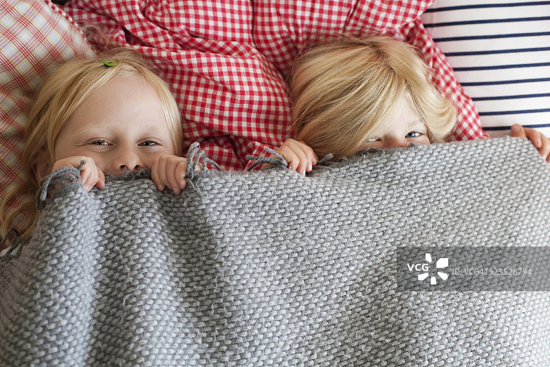两姐妹(3-4)在床上，用毯子盖着脸图片素材