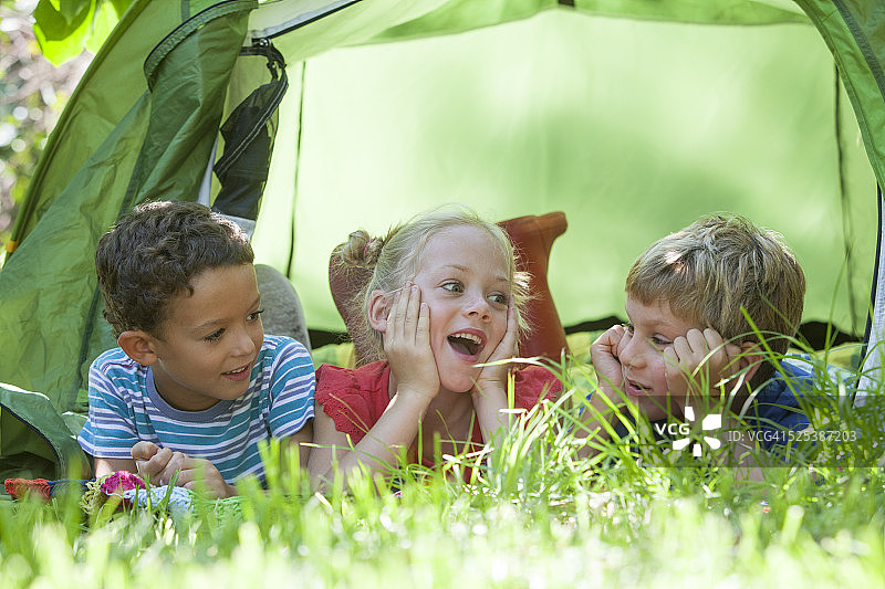 三个孩子躺在花园帐篷里聊天图片素材