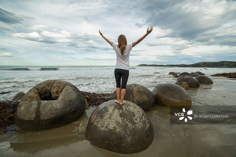 欢呼的女人站在海边一块圆石上图片素材