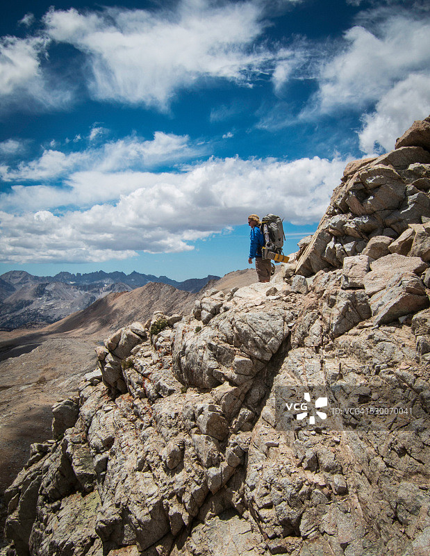 年轻人背着双肩包在岩石山上，有远景图片素材