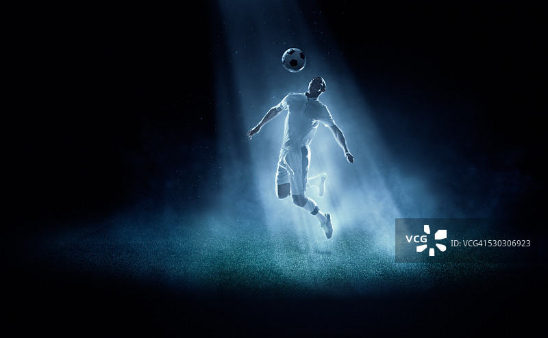 足球运动员在聚光灯下踢球图片素材
