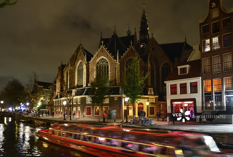 荷兰阿姆斯特丹的运河、老教堂“欧德柯克”和红灯区在夜晚灯火通明图片素材