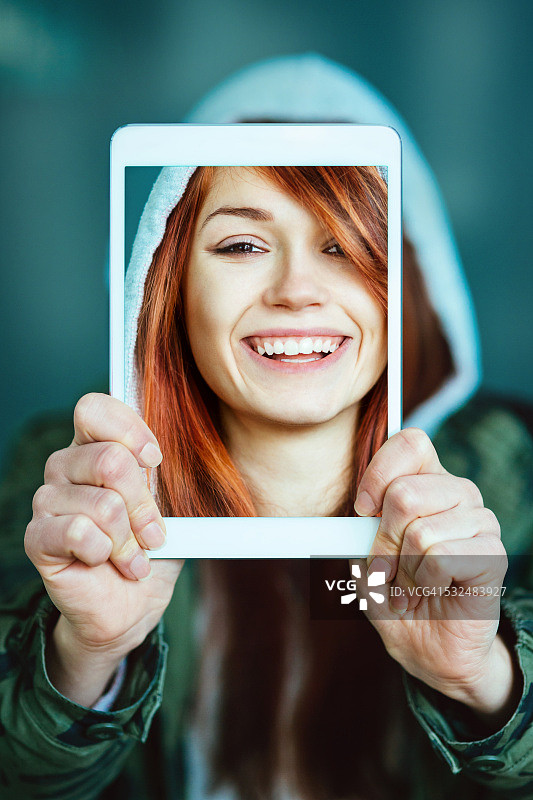 微笑的女人用平板电脑自拍图片素材