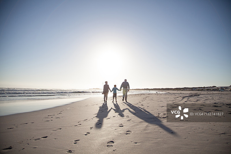 一对老年夫妇带着孙子在海滩上散步图片素材