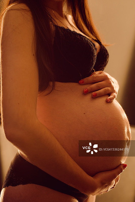 抱着肚子的孕妇，特写图片素材