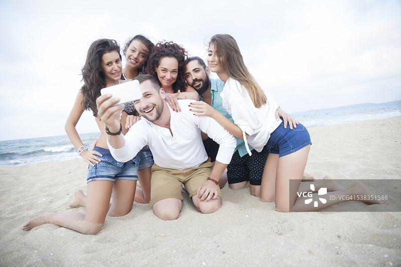 一群快乐的朋友跪在沙滩上，做自己图片素材