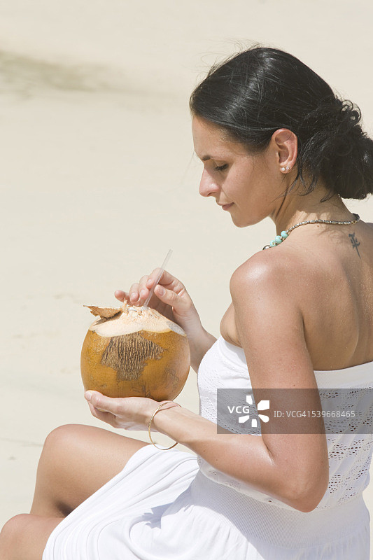 多米尼加共和国，普拉亚林孔，一个女人用椰子喝水图片素材