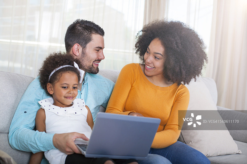 快乐的非裔美国家庭在家里使用笔记本电脑。图片素材