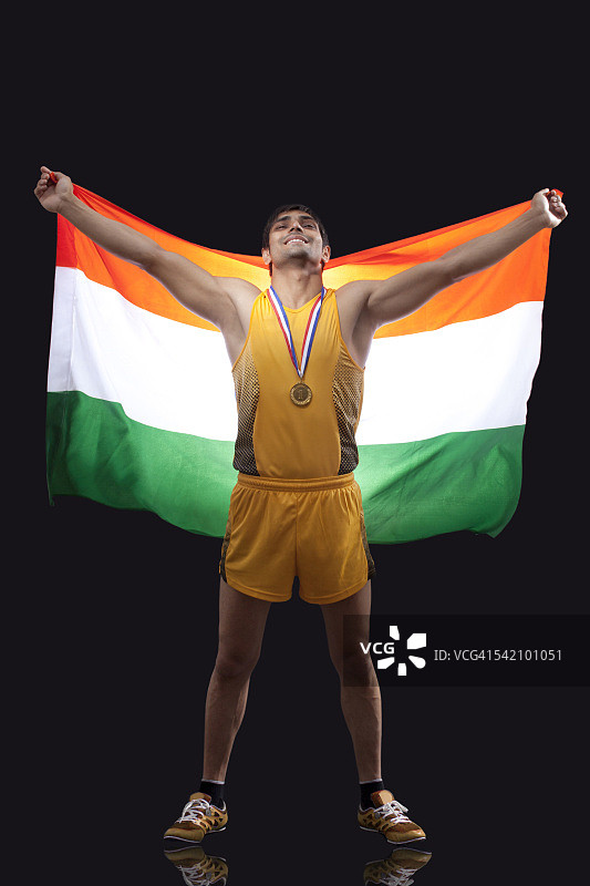 全长快乐的男性奖牌得主与印度国旗站在黑色的背景图片素材