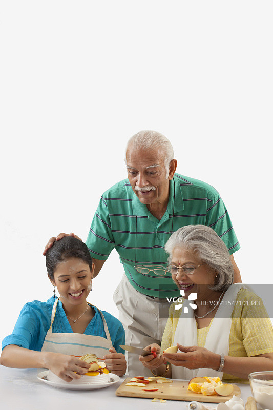 祖母和孙女在厨房干活，而祖父在一旁看着图片素材