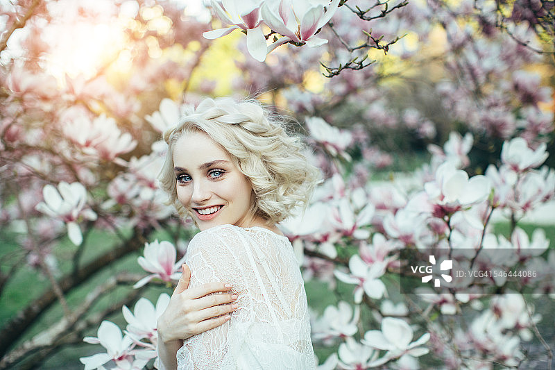 春天灌木丛背景上的美丽女孩图片素材