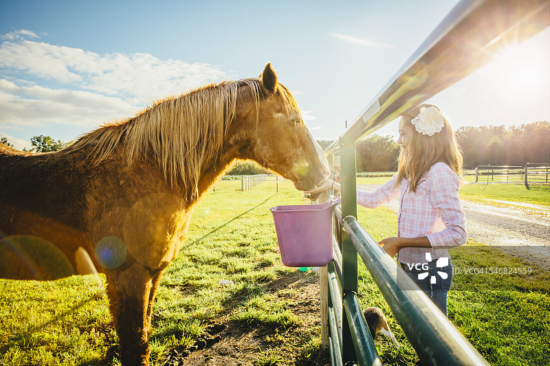 一个白人女孩在牧场喂马图片素材