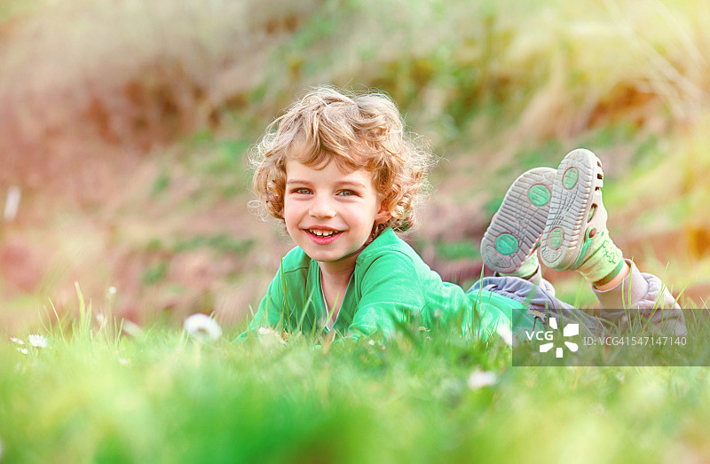 小男孩躺在草地上，微笑着图片素材