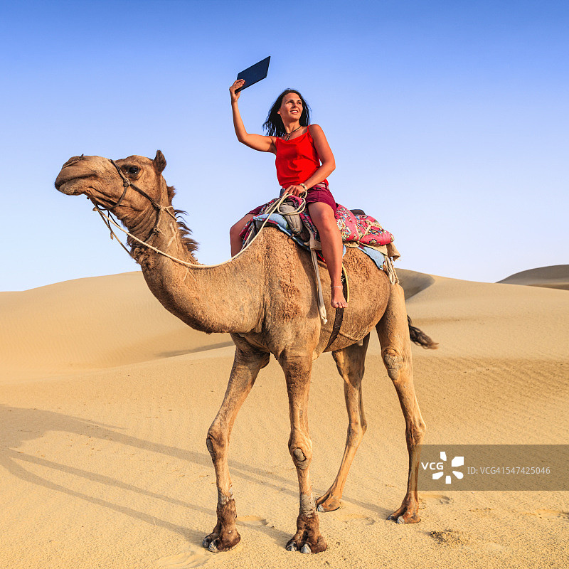 印度拉贾斯坦邦，年轻的女游客在骆驼上自拍图片素材