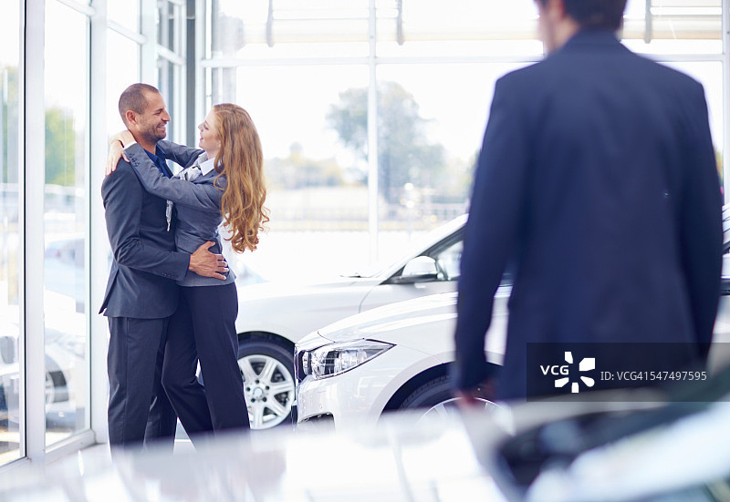 一对情侣在汽车经销商拥抱图片素材