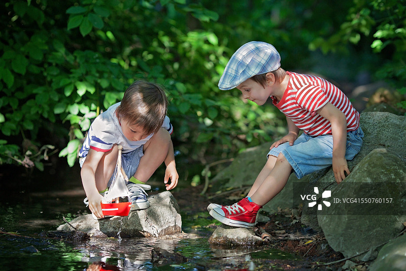 可爱的小男孩在池塘里玩玩具船图片素材