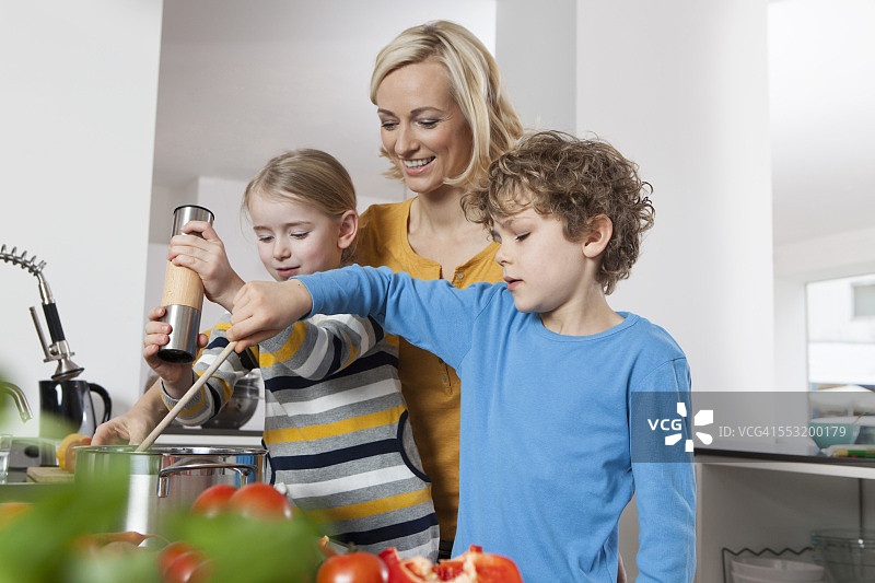 母亲，女儿和儿子在厨房做饭图片素材