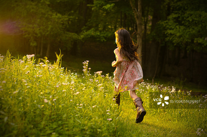 小女孩在花丛中奔跑。图片素材