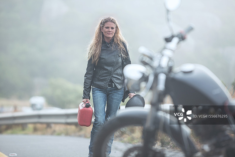 妇女走在路上，汽油罐对着摩托车图片素材