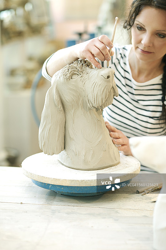 陶工在车间制作狗雕像图片素材