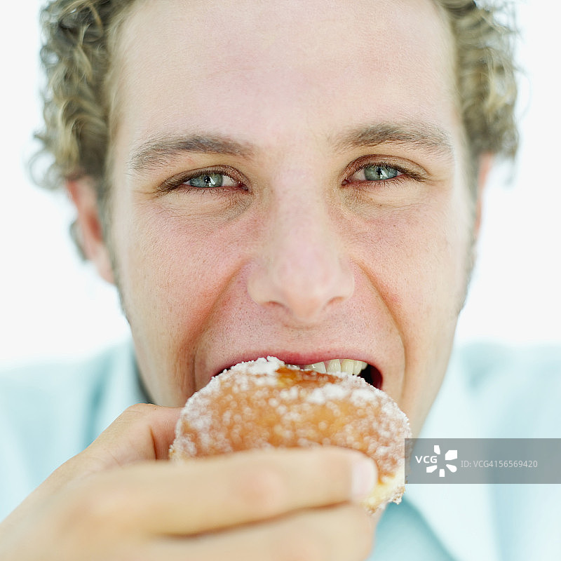 一个年轻人吃甜甜圈的特写图片素材