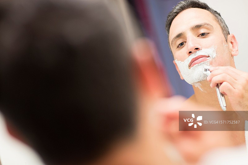 中年男人，看着镜子，刮着胡子图片素材