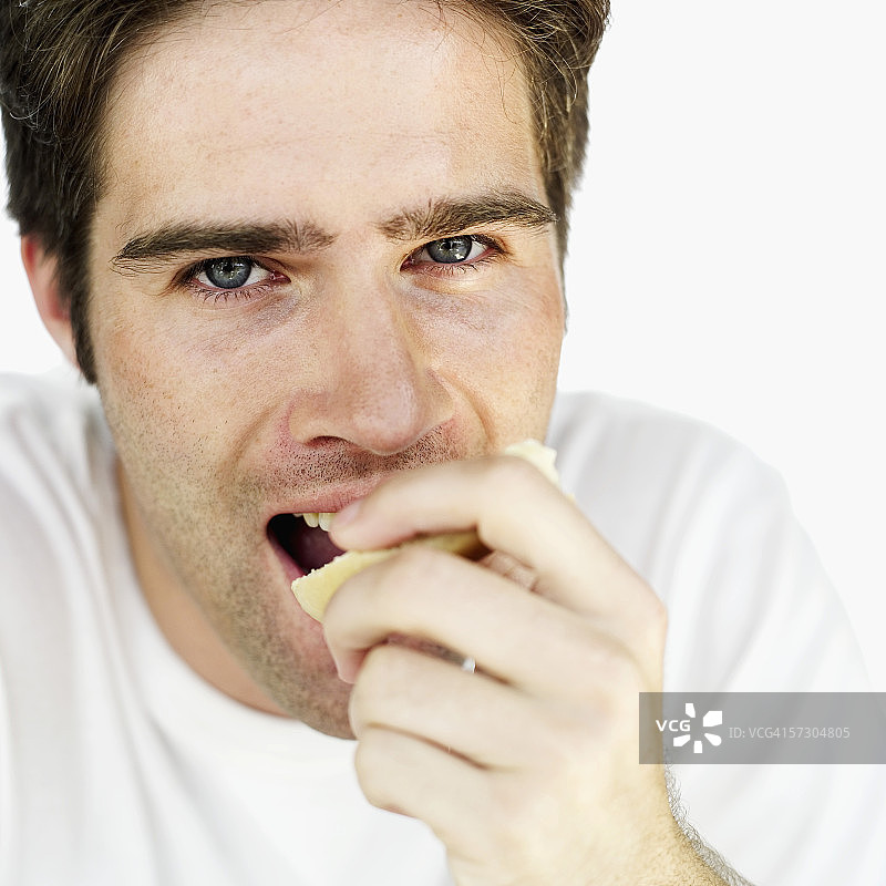 一个年轻人吃一片百吉饼的特写镜头图片素材