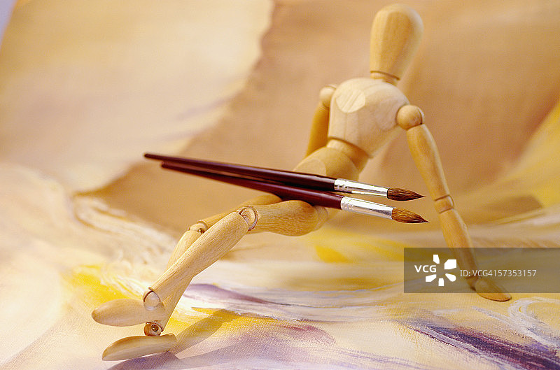 画笔放在木制小雕像的腿上图片素材