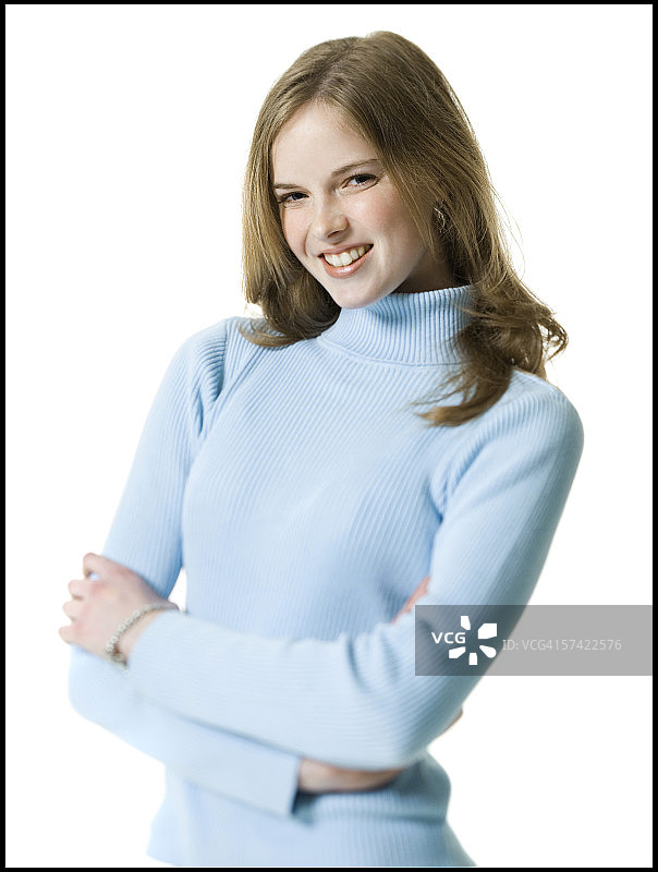 一个年轻女子的肖像，微笑着她的双臂交叉图片素材