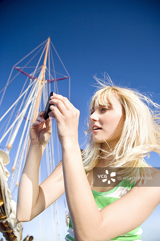 一名年轻女子在一艘帆船上用手机拍照图片素材