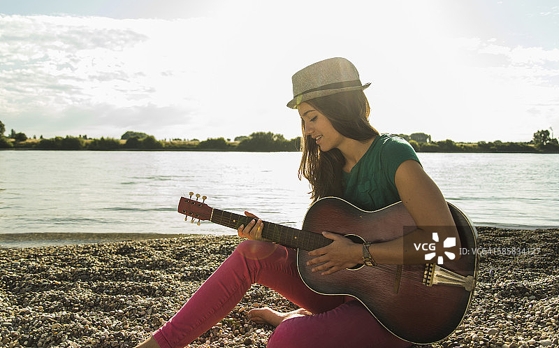 年轻女子在河边弹吉他图片素材