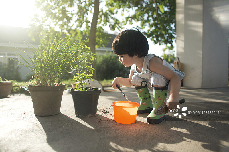 亚洲2到3岁的蹒跚学步的男孩做园艺工作。图片素材