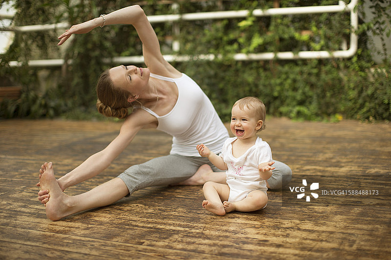 女人做瑜伽锻炼，而婴儿有乐趣图片素材