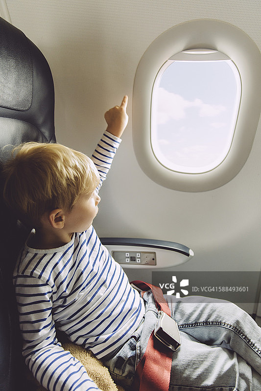 小男孩指着飞机窗外图片素材