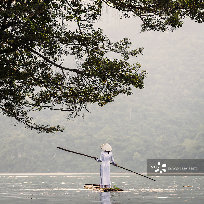 年轻女子用竹筏撑过湖面图片素材