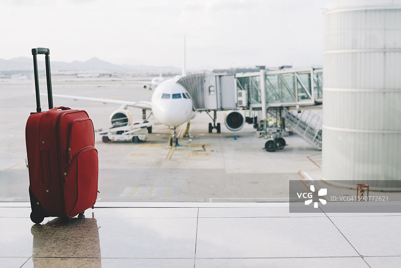 机场的红色行李箱，背景是飞机图片素材