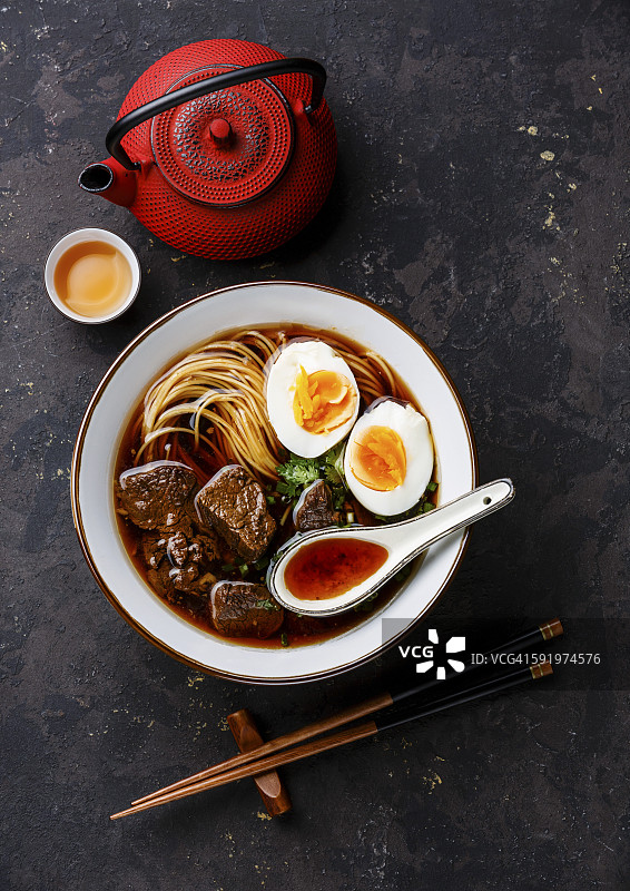 亚洲面条汤，慢煮牛肉和鸡蛋，深色背景图片素材