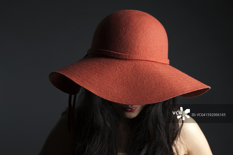 亚洲女人躲在红帽子后面图片素材