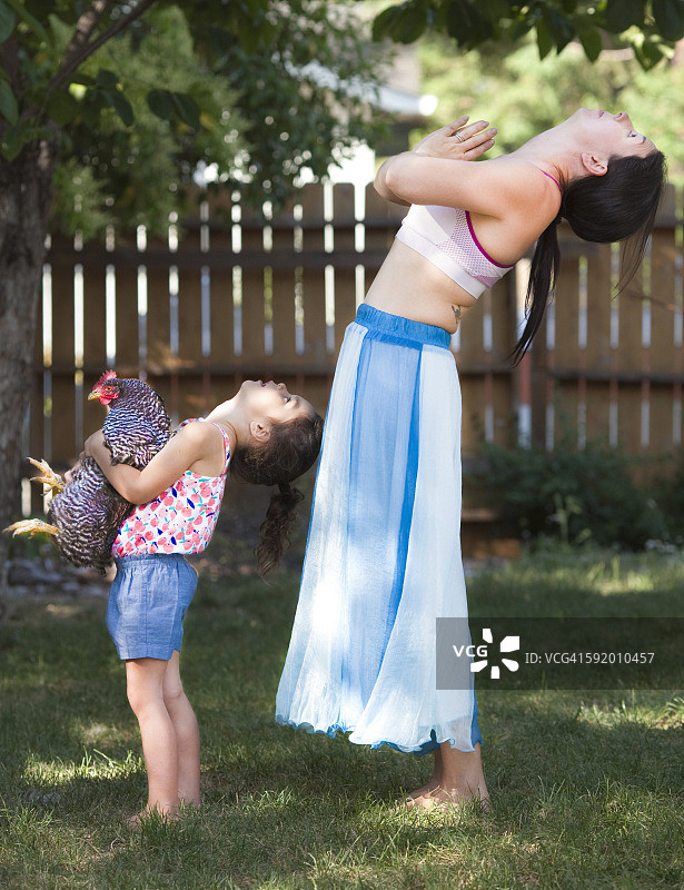 母亲和女儿在后院练瑜伽，鸡肉图片素材
