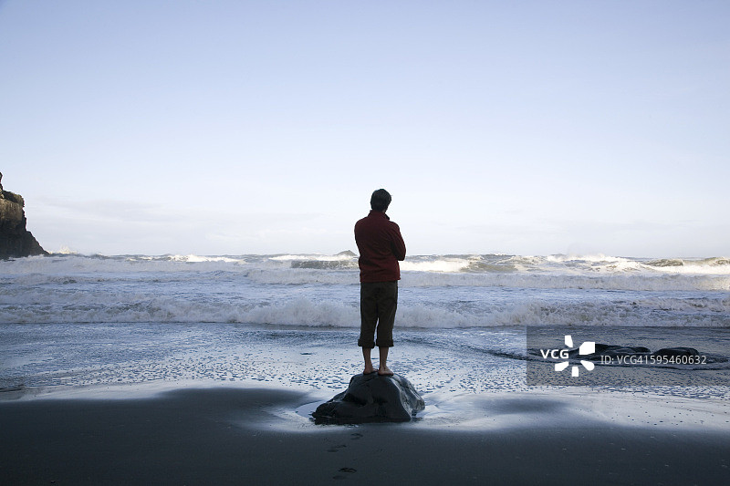 一个人站在海滩的岩石上，后视镜图片素材
