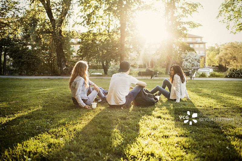 青少年坐在公园的草地上图片素材