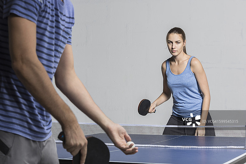 坚定的年轻女子与男子打乒乓球图片素材