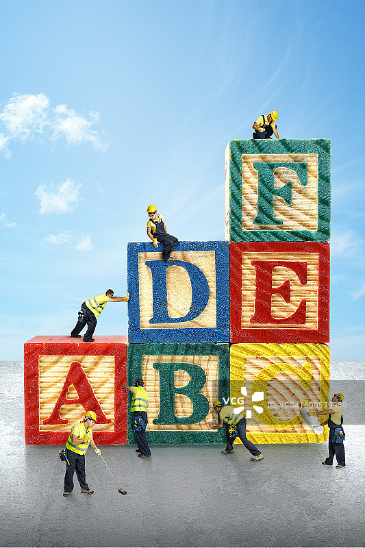 微型建筑工人举起玩具字母积木图片素材