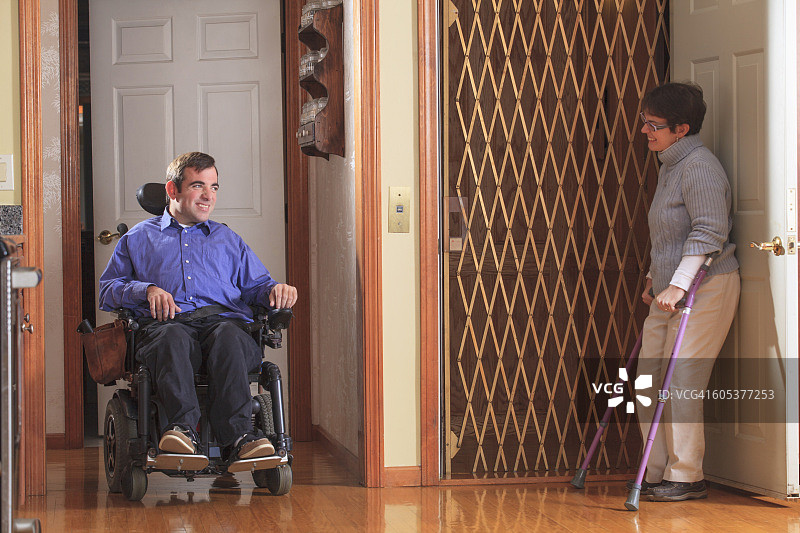 患有脑瘫的妇女用电动轮椅帮助患有脑瘫的男子进入家庭电梯图片素材