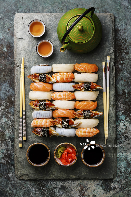 手握寿司为两套，放在灰色石板板和绿茶板上图片素材